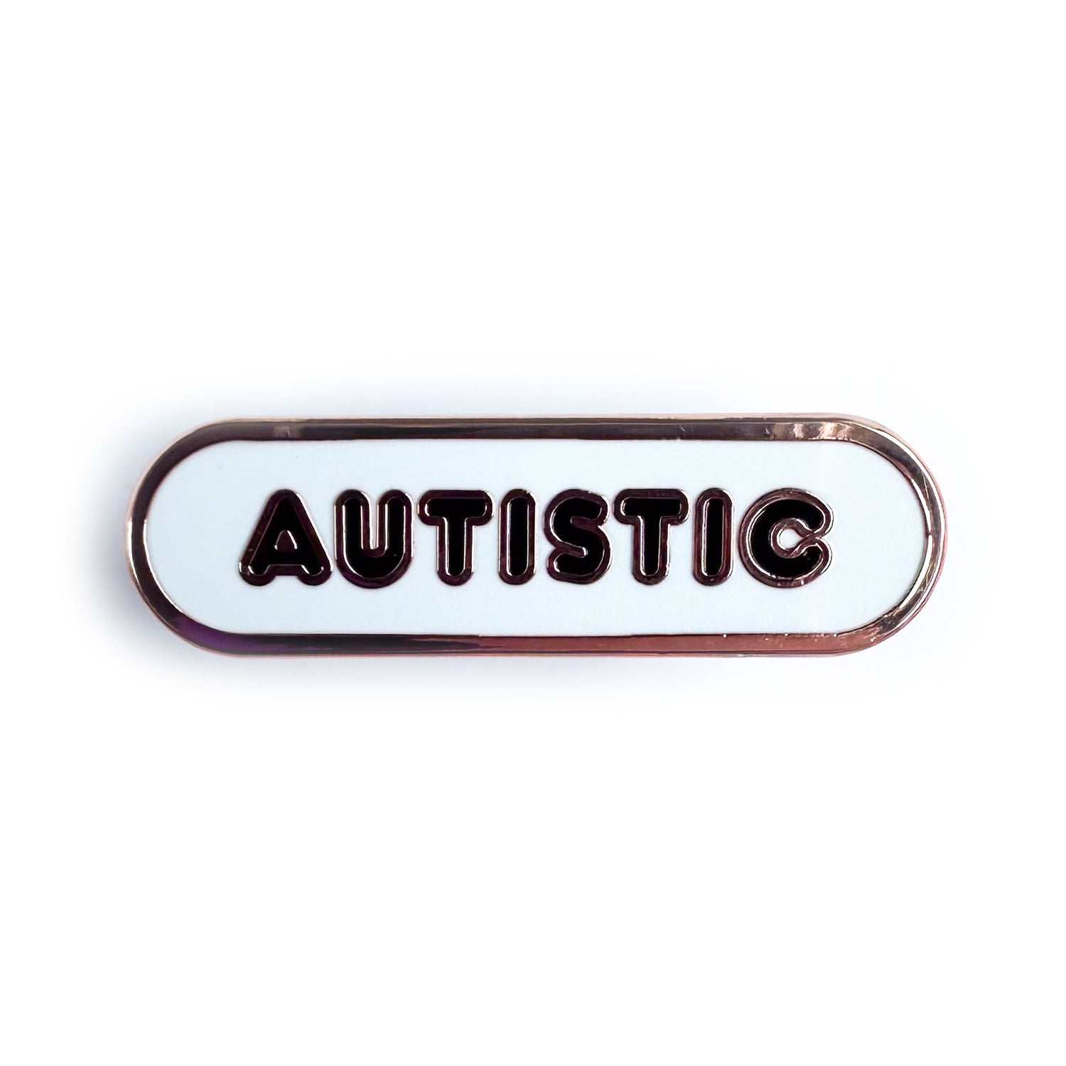 A white capsule shaped pin with black bubble letters that read "Autistic"