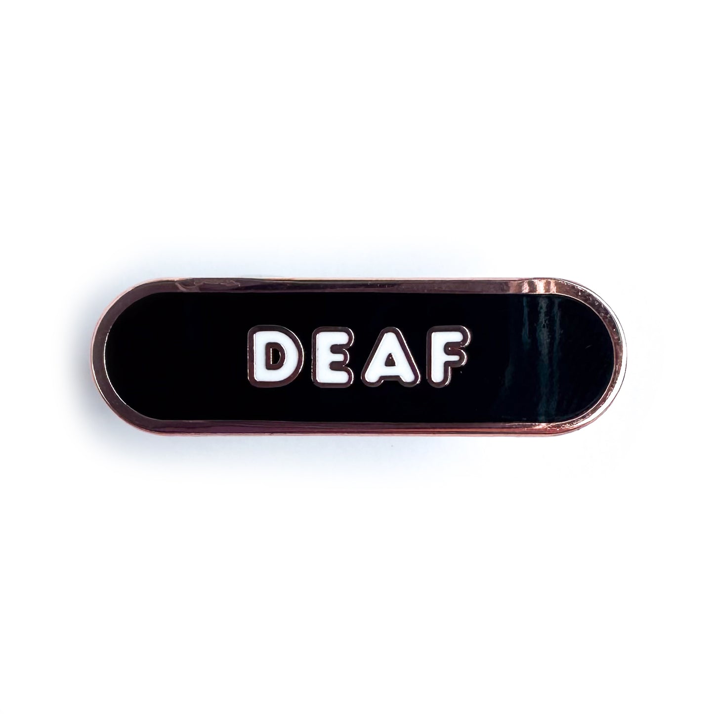 A black capsule shaped enamel pin with the word "Deaf" on it in white bubble letters.