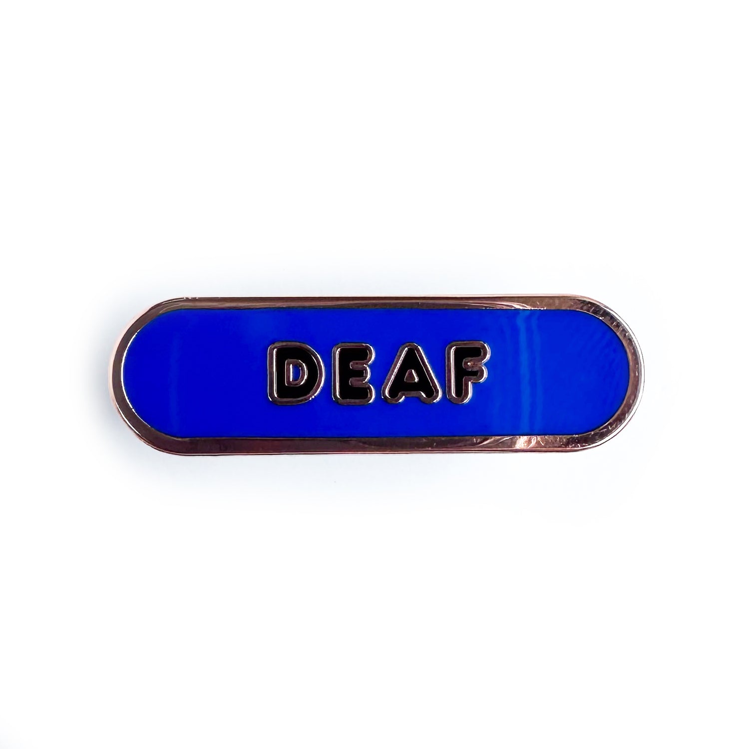 A blue capsule shaped pin with black bubble letters that spell "Deaf" on it. 