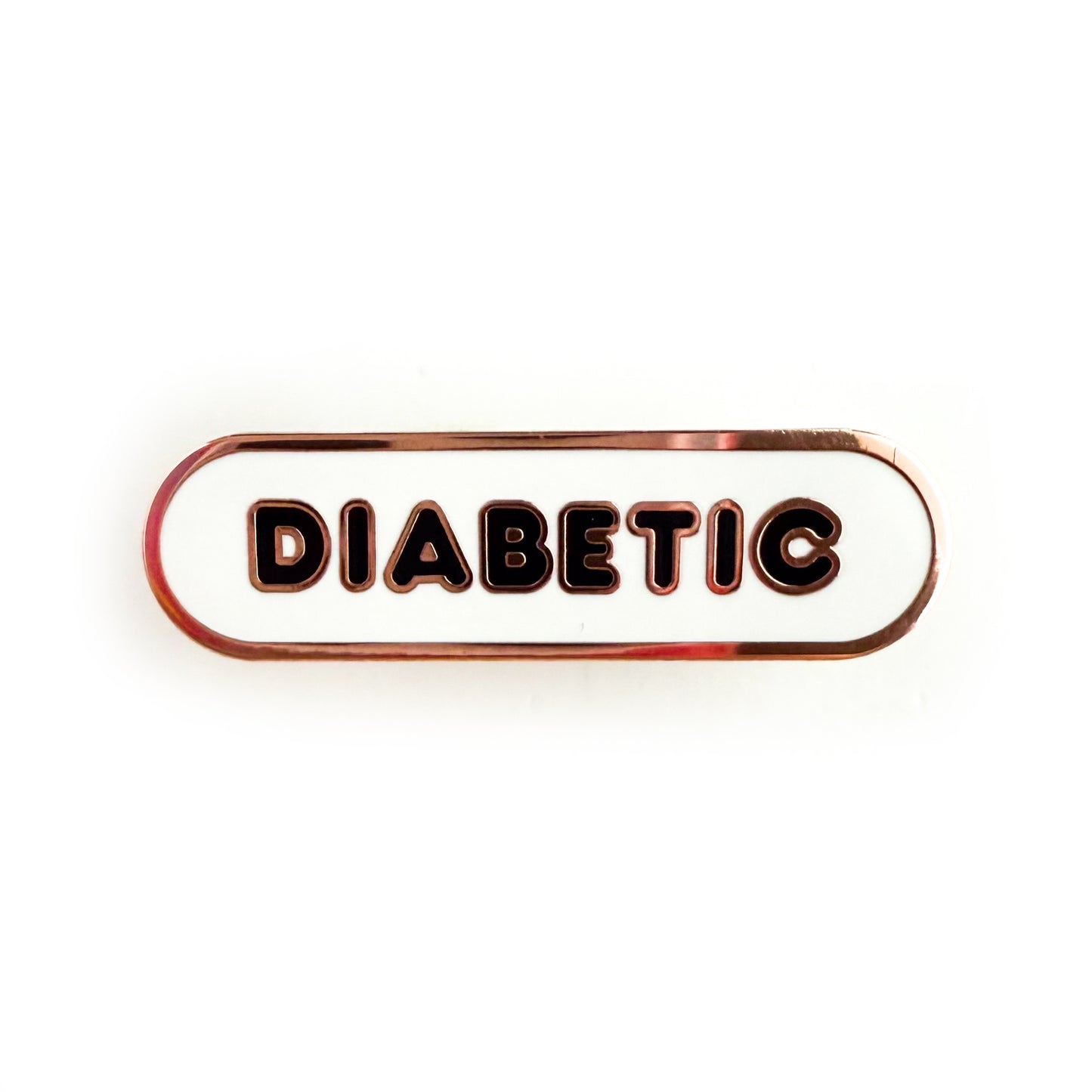 A bandaid shaped pin with the text DIABETIC in bubble letters. The background is white and the text is black.