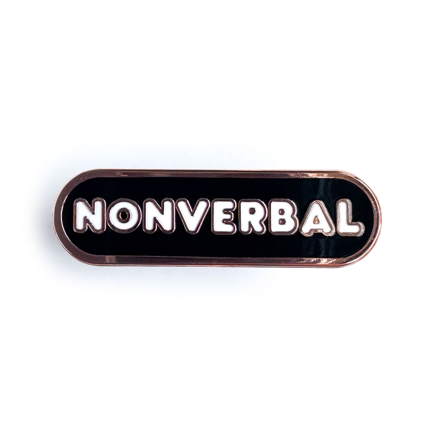 A black enamel pin that has white bubble letters that read "Nonverbal." 