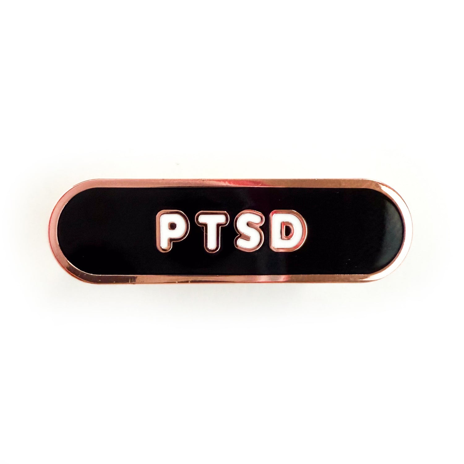 A bandaid shaped pin with the text PTSD in bubble letters. The background is black and the text is white.