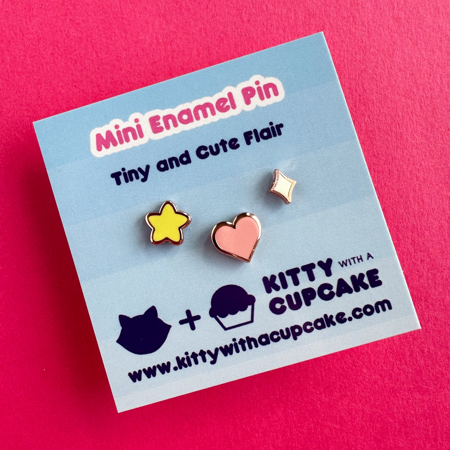 A square card with three enamel pins packaged on it. The card reads "mini Enamel pin - Tiny and Cute Flair". The pins are three different shapes, a yellow puffy star, a pink heart and a diamond sparkle. 