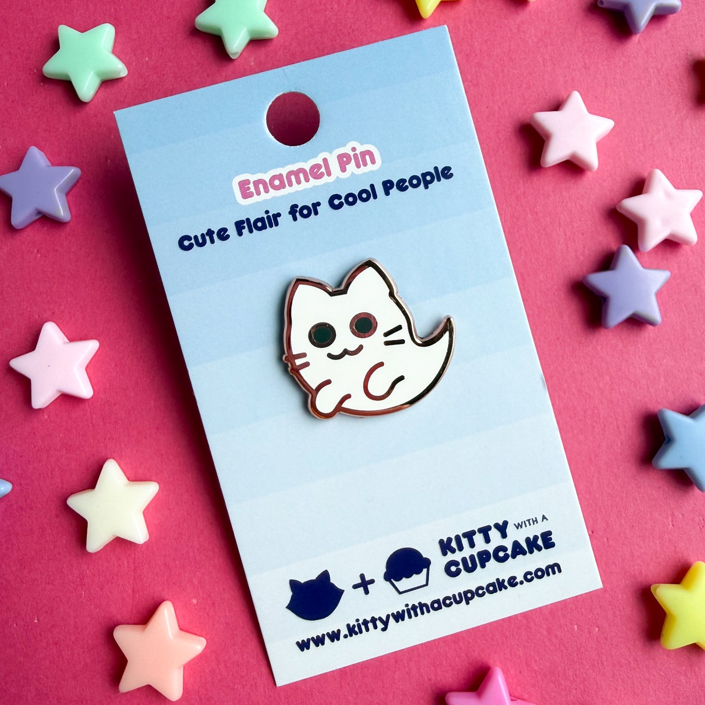 A cute ghost kitty shaped enamel pin packaged on a blue card background. The card reads "Enamel Pin - Cute Flair for Cool People" and has the Kitty With a Cupcake logo at the bottom.