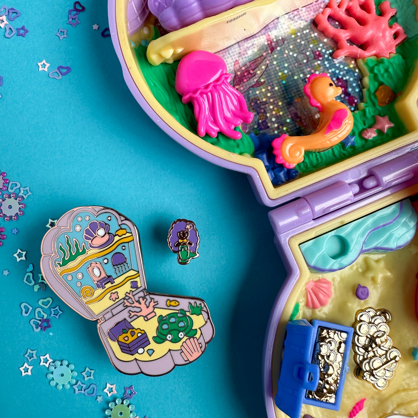 The mermaid pocket pin set is sitting next to a real Polly Pocket mermaid toy 