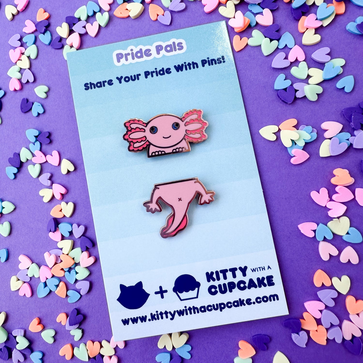 A card that reads "Pride Pals" with two pins on it each repressing the top and bottom half of a pink axolotl.
