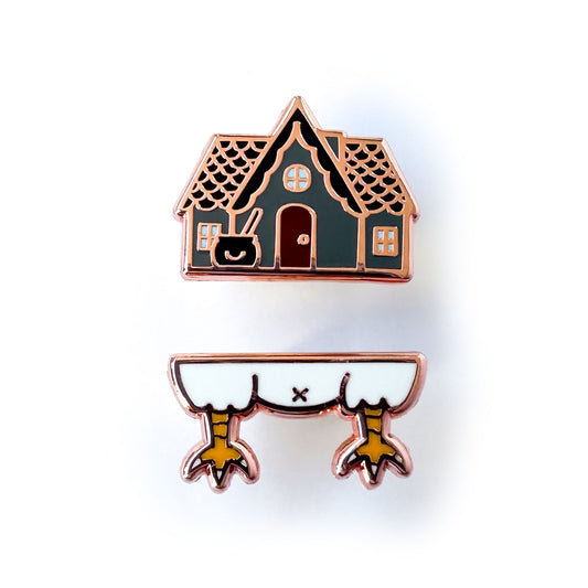 Baba Yaga's house represented as two pins, the top pin is a grey house with a cauldron in front and the bottom pin is chicken legs.