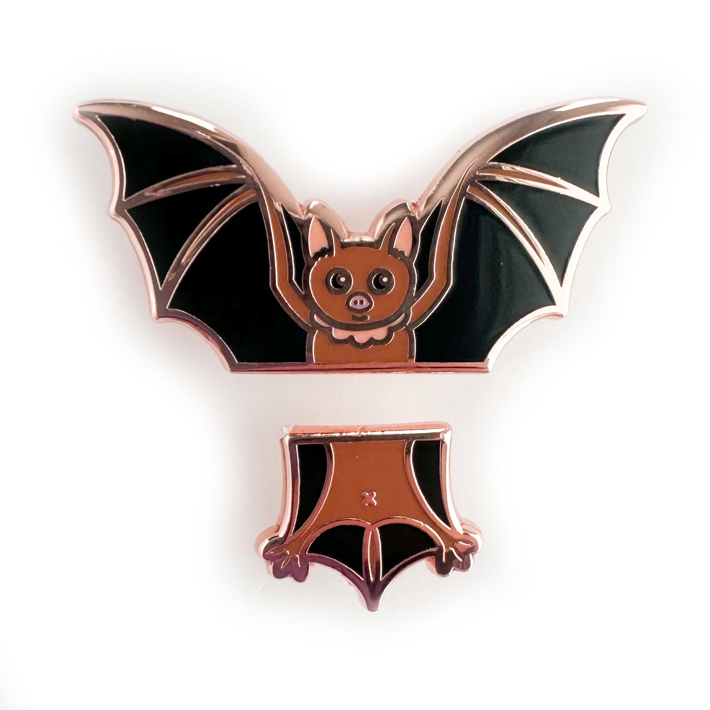 A set of enamel pins that come together to form a cute illustration of a bat, the top pin is the head and wings, the bottom is the tail and legs. 