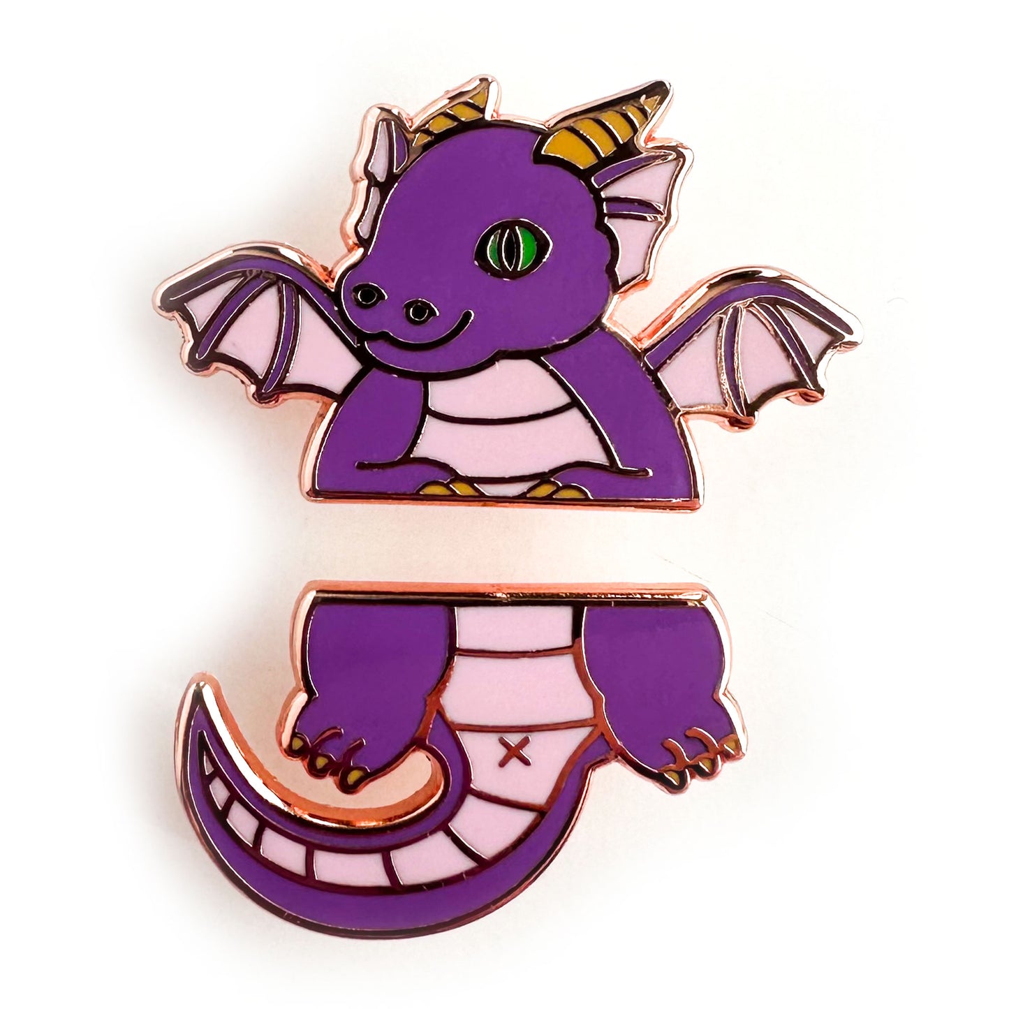 Two enamel pins that come together to form a cute cartoon dragon split in half horizontally. The top pin is the head, wings and arms. The bottom half is the legs and tail. The dragon is purple with a green eye and yellow horns. 