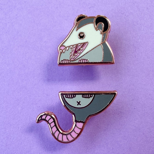 Two pins that come together in the middle to form a cute illustration of an opossum with its mouth open. 