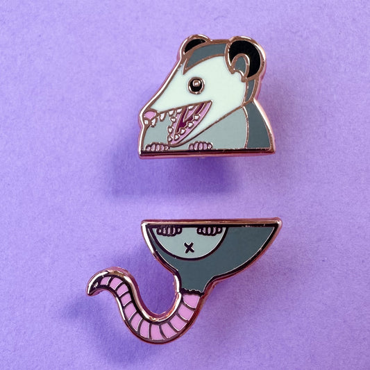 Two pins that come together in the middle to form a cute illustration of an opossum with its mouth open.