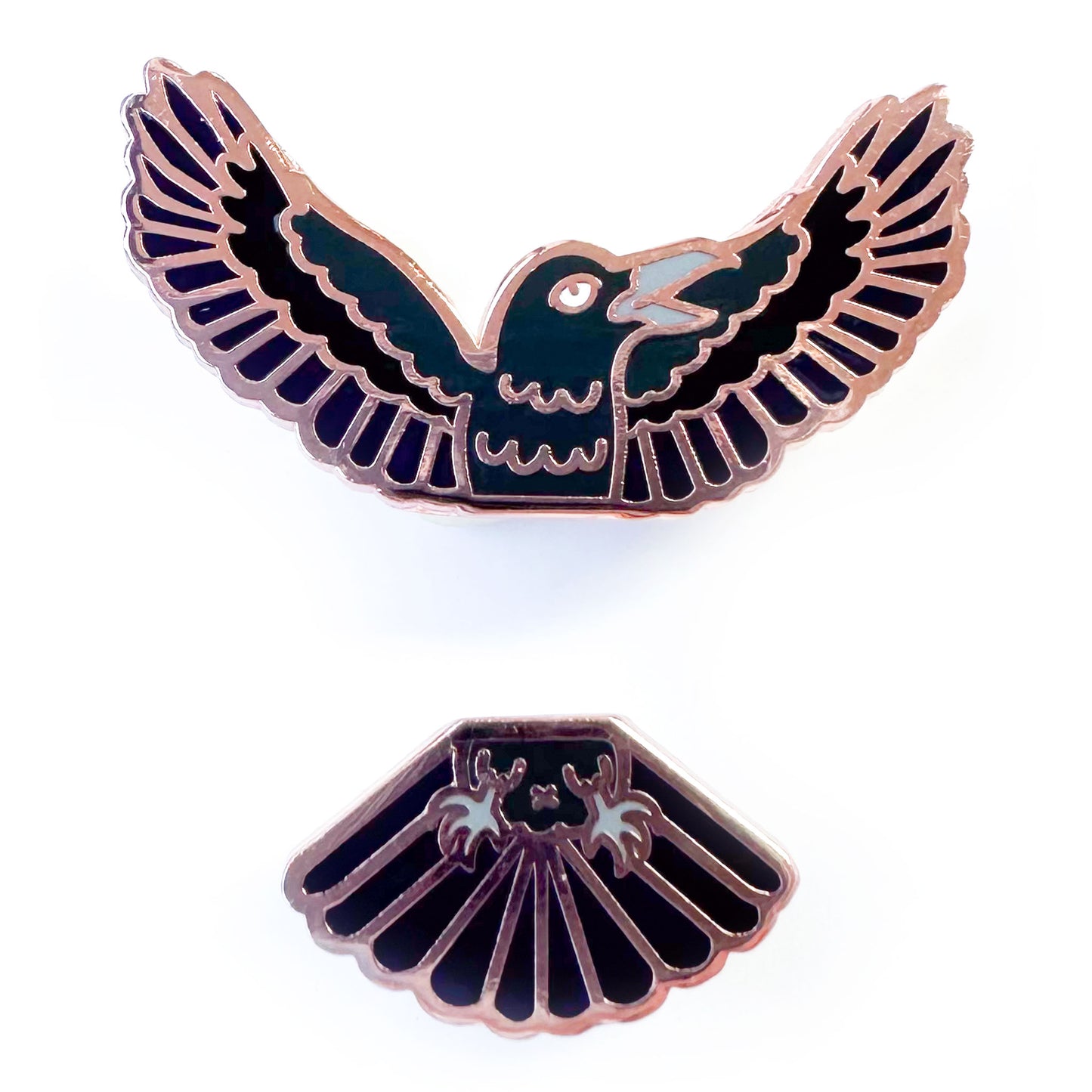 Two enamel pins that come together in the middle to form a raven, one pin is the head and wings and one pin is the tail feathers and feet. 