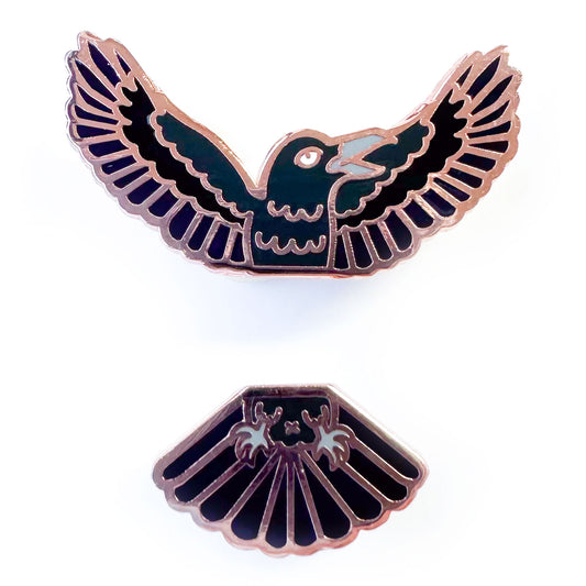 Two enamel pins that come together in the middle to form a raven, one pin is the head and wings and one pin is the tail feathers and feet.