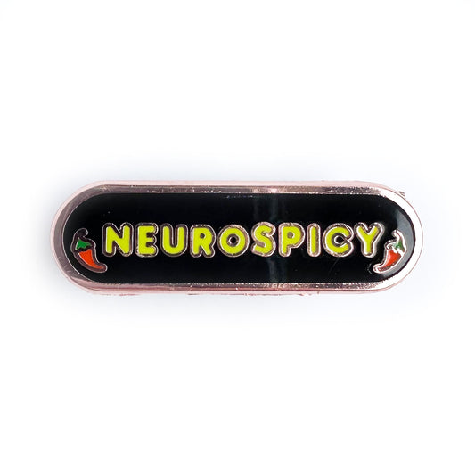 A capsule shaped pin with "Neurospicy" on it in neon green bubble letters and little illustrations of chili peppers around the words. The background of the pin is black. 