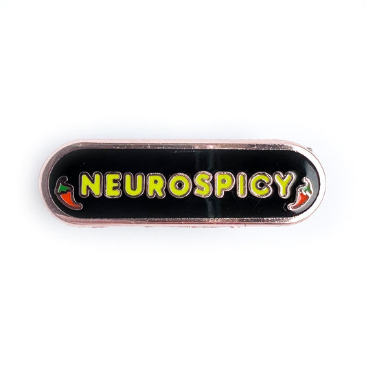 A capsule shaped pin with "Neurospicy" on it in neon green bubble letters and little illustrations of chili peppers around the words. The background of the pin is black.