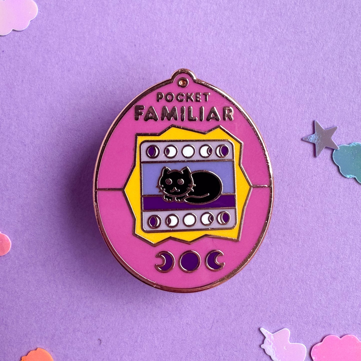 The pocket familiar pink virtual pet pin on a lavender confetti background.