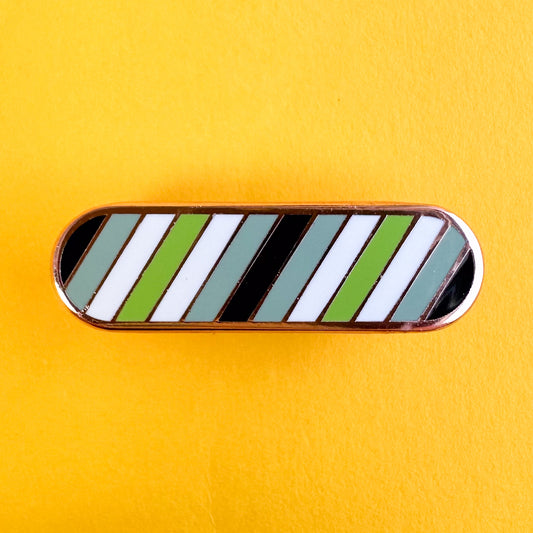 An oval shaped pin with diagonal stripes in the colors of the agender pride flag on yellow background.