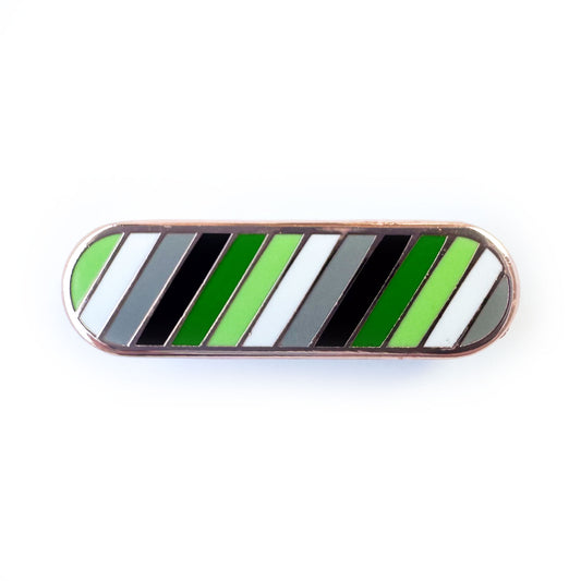 A bandaid shaped pin with diagonal bands of color in the colors of the Aromantic Pride Flag, green, light green, white, grey and black. 