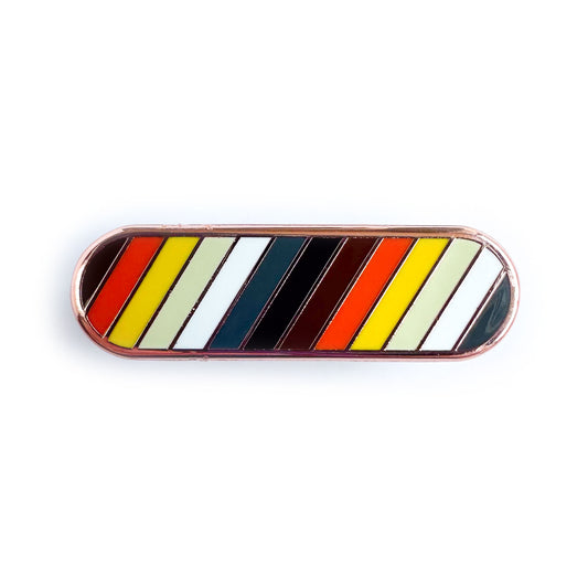 A capsule shaped pin with the colors of the International Bear Brotherhood Flag or Bear Pride Flag in diagonal stripes