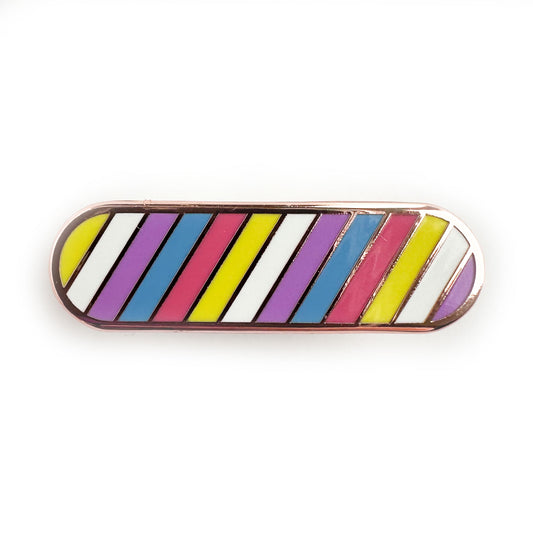 A capsule shaped enamel pin in the colors of the bigender pride flag.