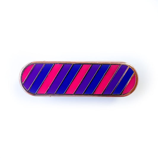 A bandaid shaped enamel pin with diagonal stripes in pink, purple, and blue which are the colors of the Bi Pride Flag. 