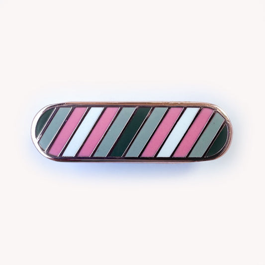 A bandaid shaped pin with grey, light grey, baby pink, and white stripes which are the colors of the Demigirl pride flag.