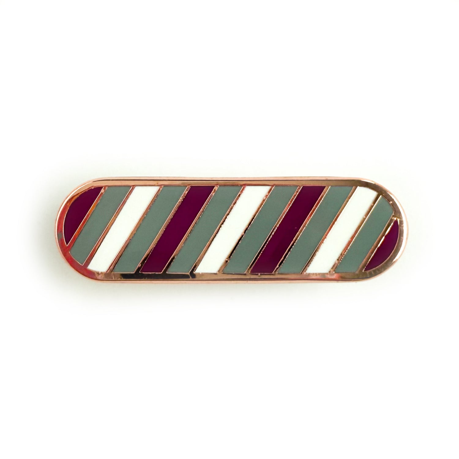A bandaid shaped pin with diagonal bands of color on it in gray, purple, and white representing the gray asexual or gray ace flag.