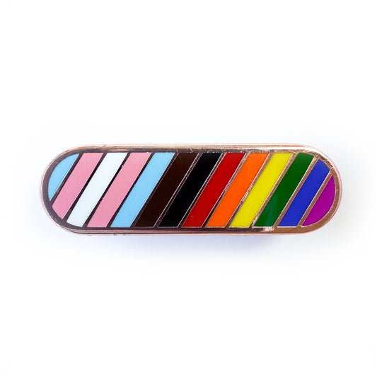 A capsule shaped pin with diagonal stripes in the colors of the progress pride flag. 