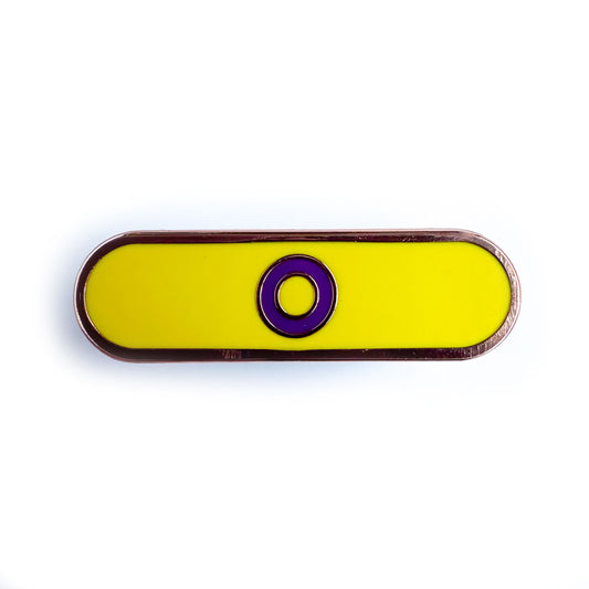 A capsule shaped pin that has a purple circle on a yellow background to represent the Intersex Pride Flag.