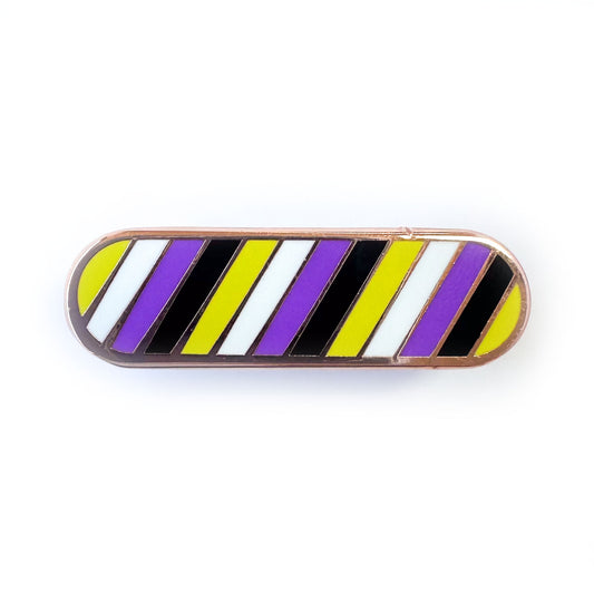 A capsule shaped enamel pin in the colors of the Nonbinary pride flag; yellow, white, purple and black.