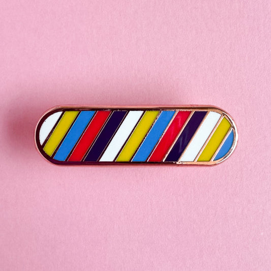 An oval shaped enamel pin in the colors of the new Polyamorous Pride Flag in diagonal stripes across it. The pin is on a pink paper background. 