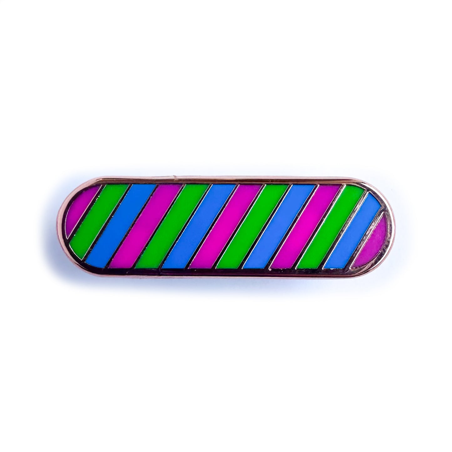 A capsule shaped enamel pin in the colors of the polysexual pride flag, pink, green and blue.