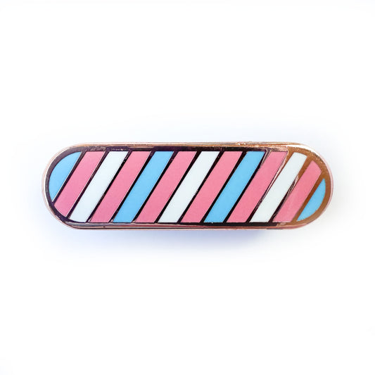 A capsule shaped pin with diagonal stripes in the colors of the transgender pride flag, light blue, light pink, and white. 