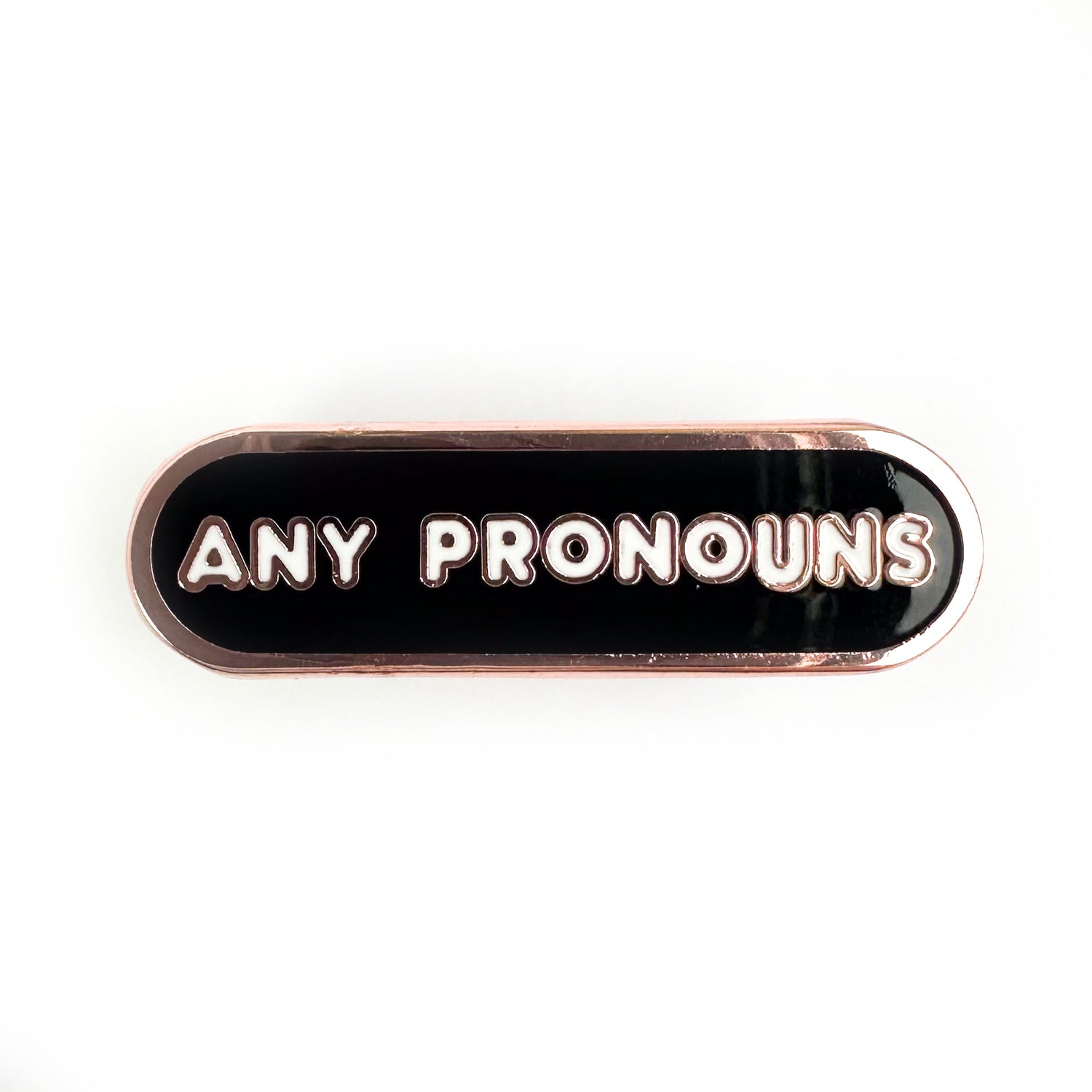 A black bandaid shaped pin with the words "any pronouns" on it. 