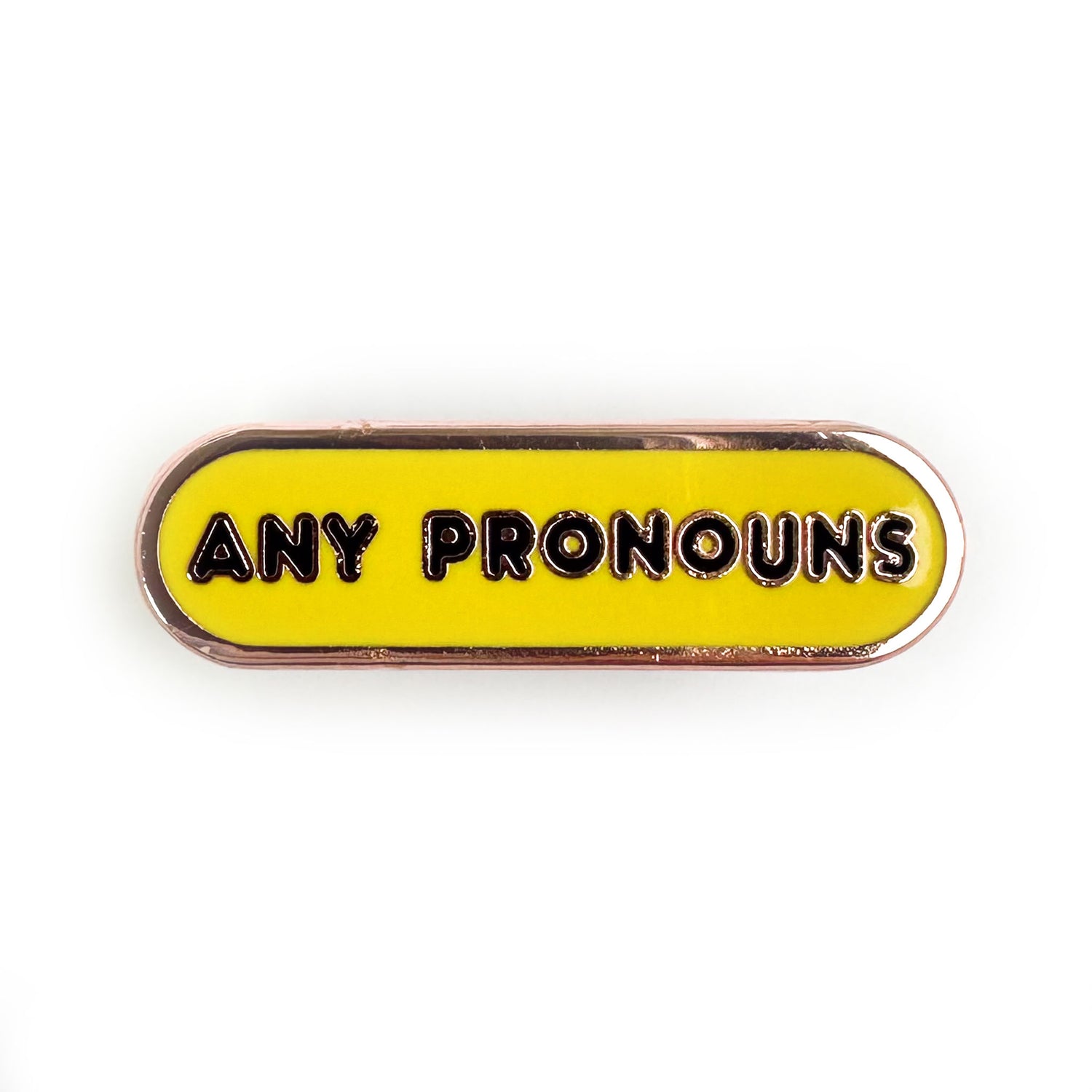 A bandaid shaped pin that is yellow with black words on it that read "Any Pronouns" 