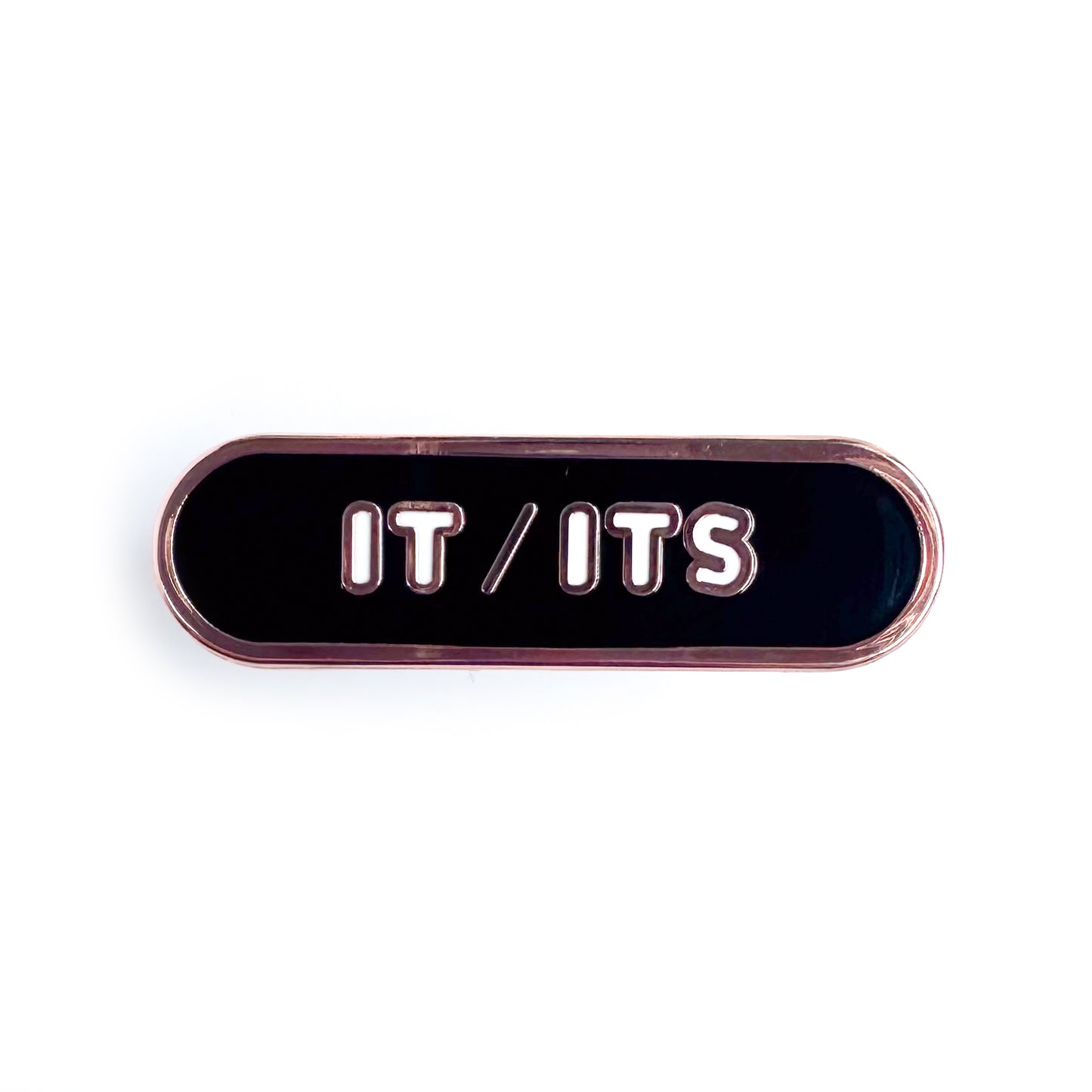 A black capsule shaped pin with white bubble letters that read "It/Its"