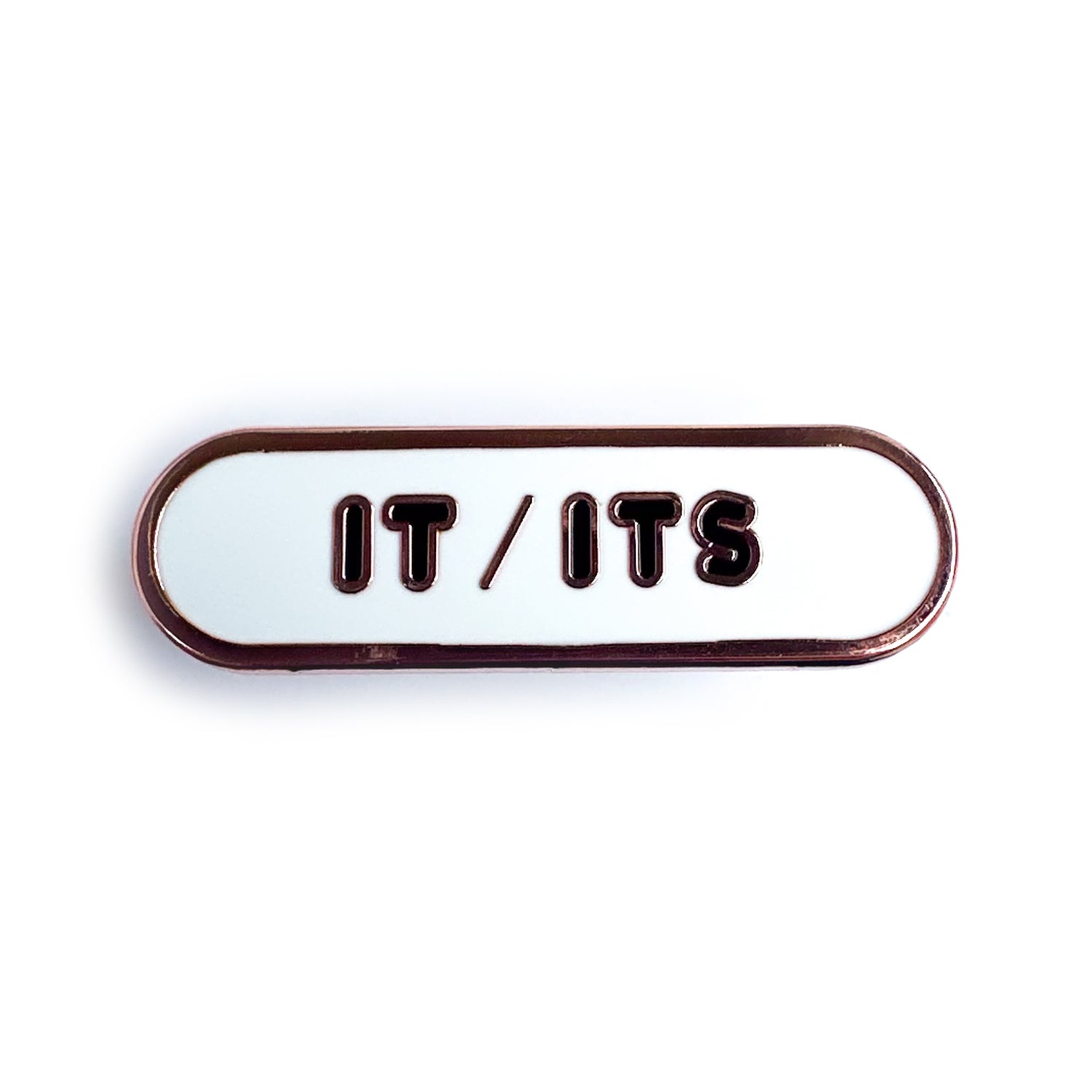 A white capsule shaped enamel pin with black bubble letters that spell "It/Its"