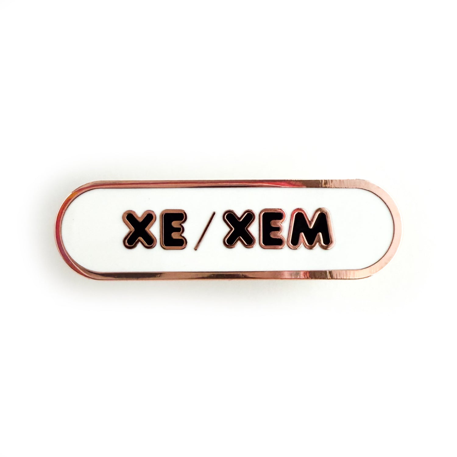 A bandaid shaped pin with the text XE/XEM in bubble letters. The background is white and the text is black.