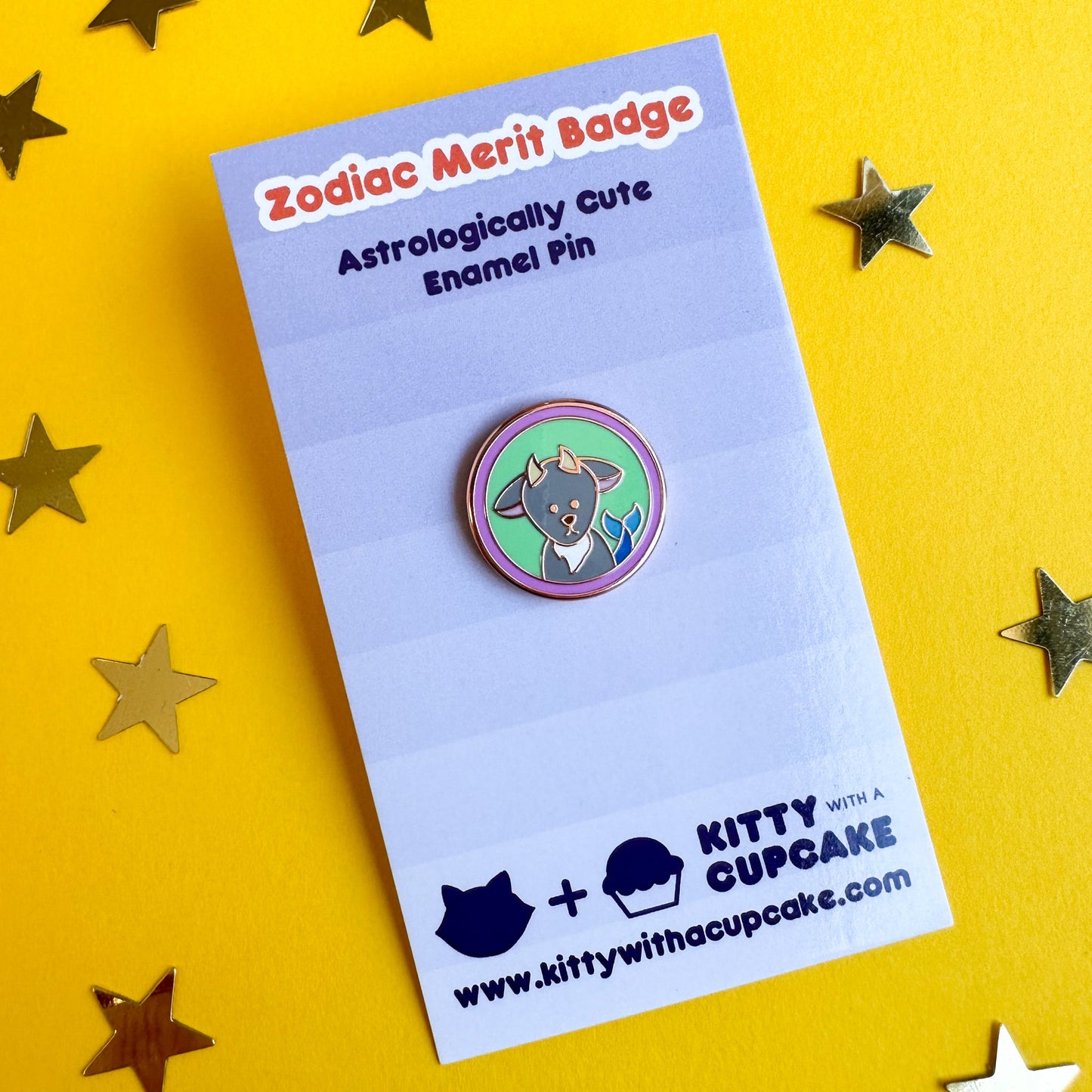 A circular enamel pin with a sea goat on it packaged on a card that reads "Zodiac Merit Badge".