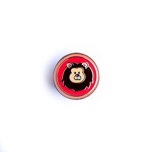 A circular enamel pin with a cute lion illustration in it to represent the Leo zodiac sign.