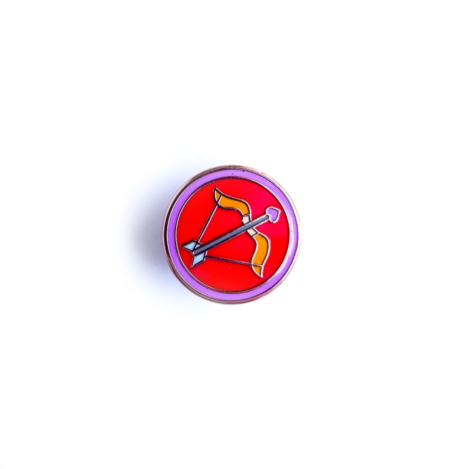 A pin of a red circle with a pink boarder with a bow and arrow in the center of the red circle to represent the Sagittarius zodiac sign. The arrow has a heart for an arrow head.
