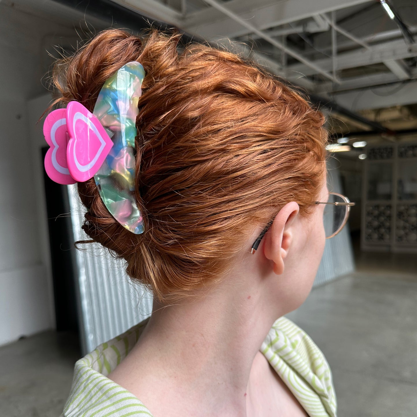 A white woman with red hair wearing the big heart claw clip with all of her hair up and contained in it. 