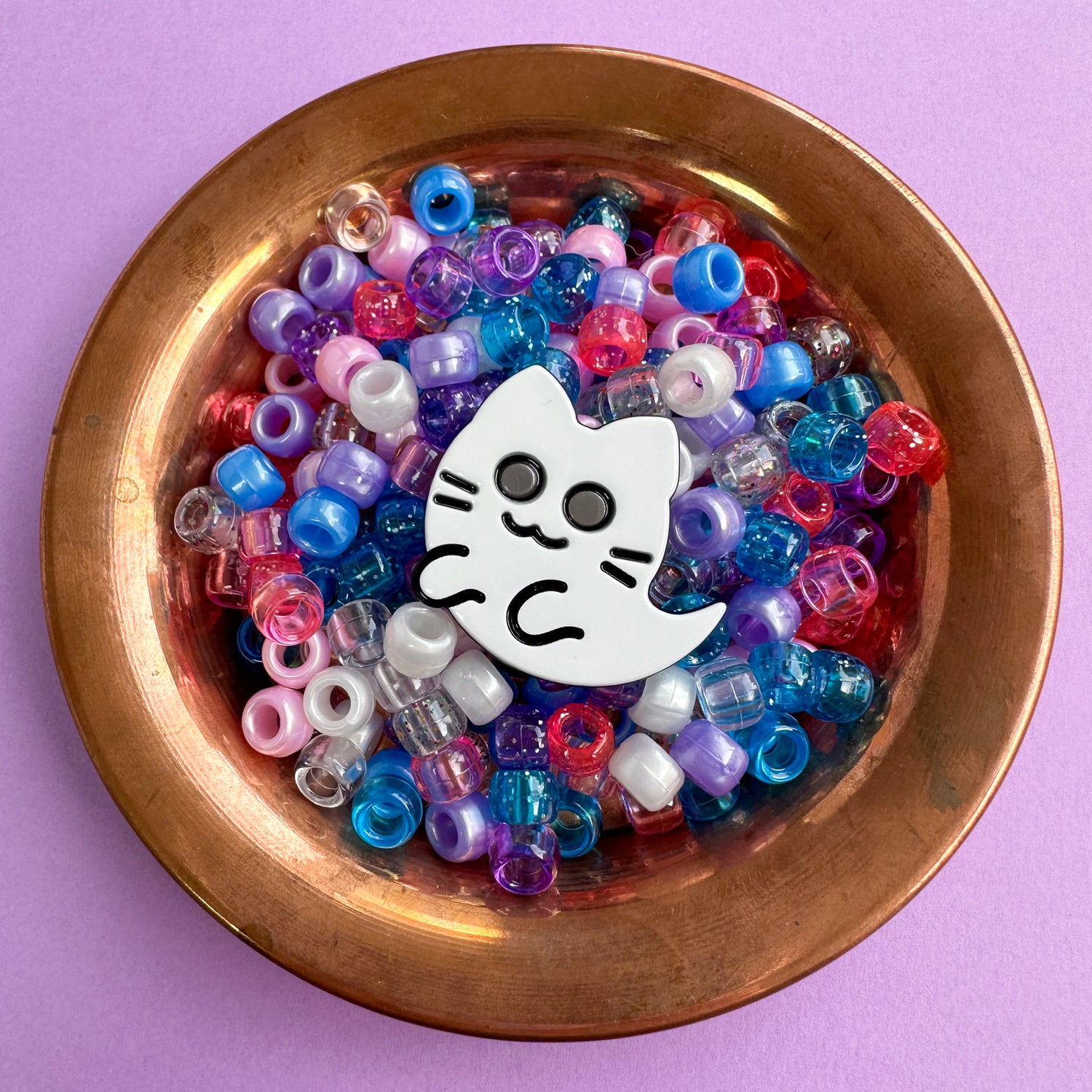 Ghost kitty acetate hair clip in a copper bowl filled with blue, pink and purple pony beads. 