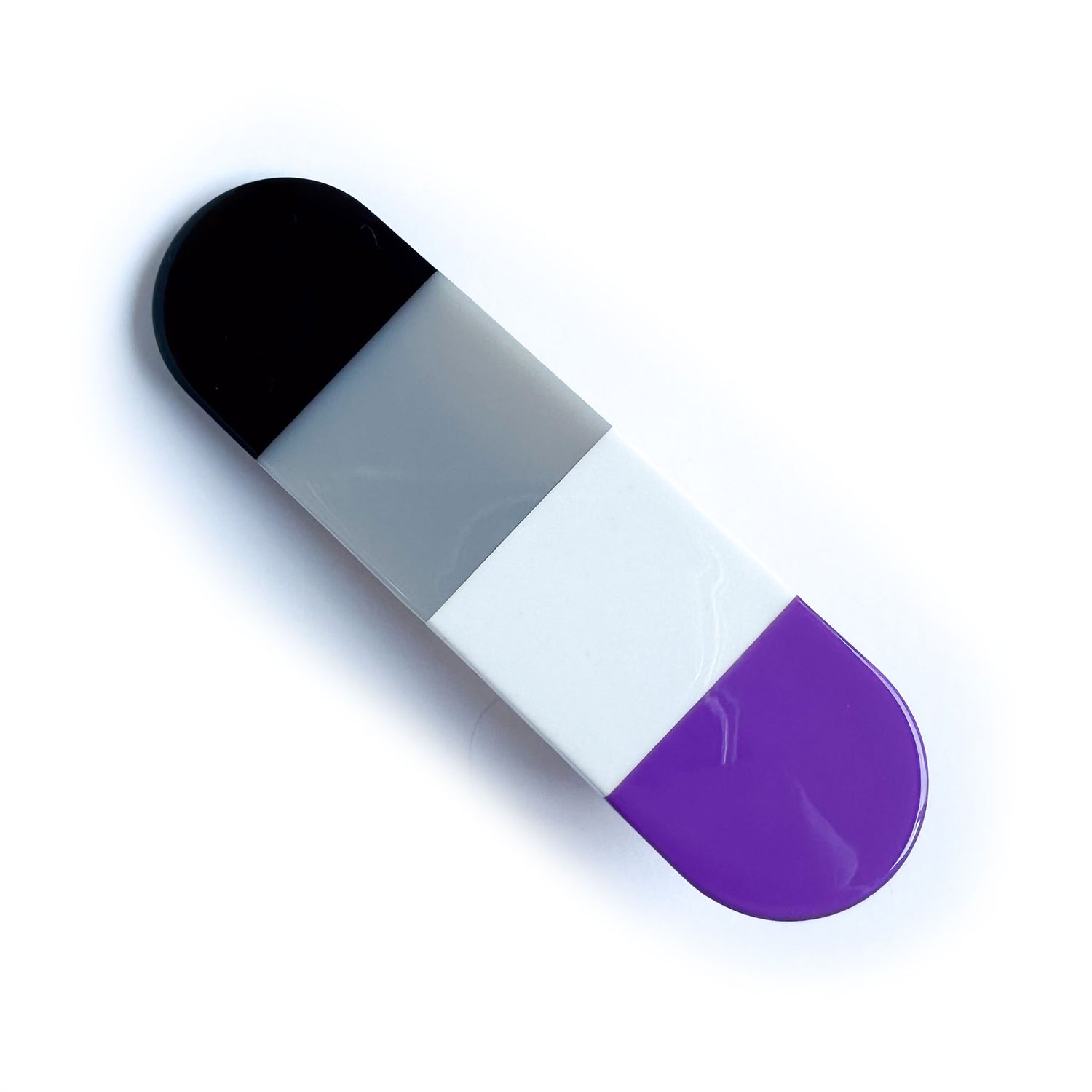 A capsule shaped acetate hair clip with vertical stripes of the Asexual Pride Flag.