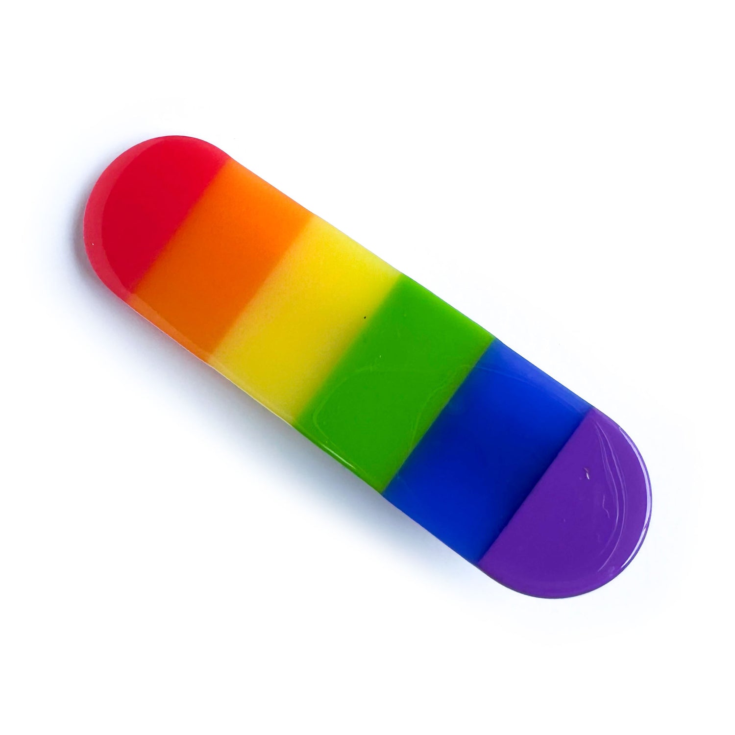 A capsule shaped hair clip with vertical stripes in the colors of the rainbow. 