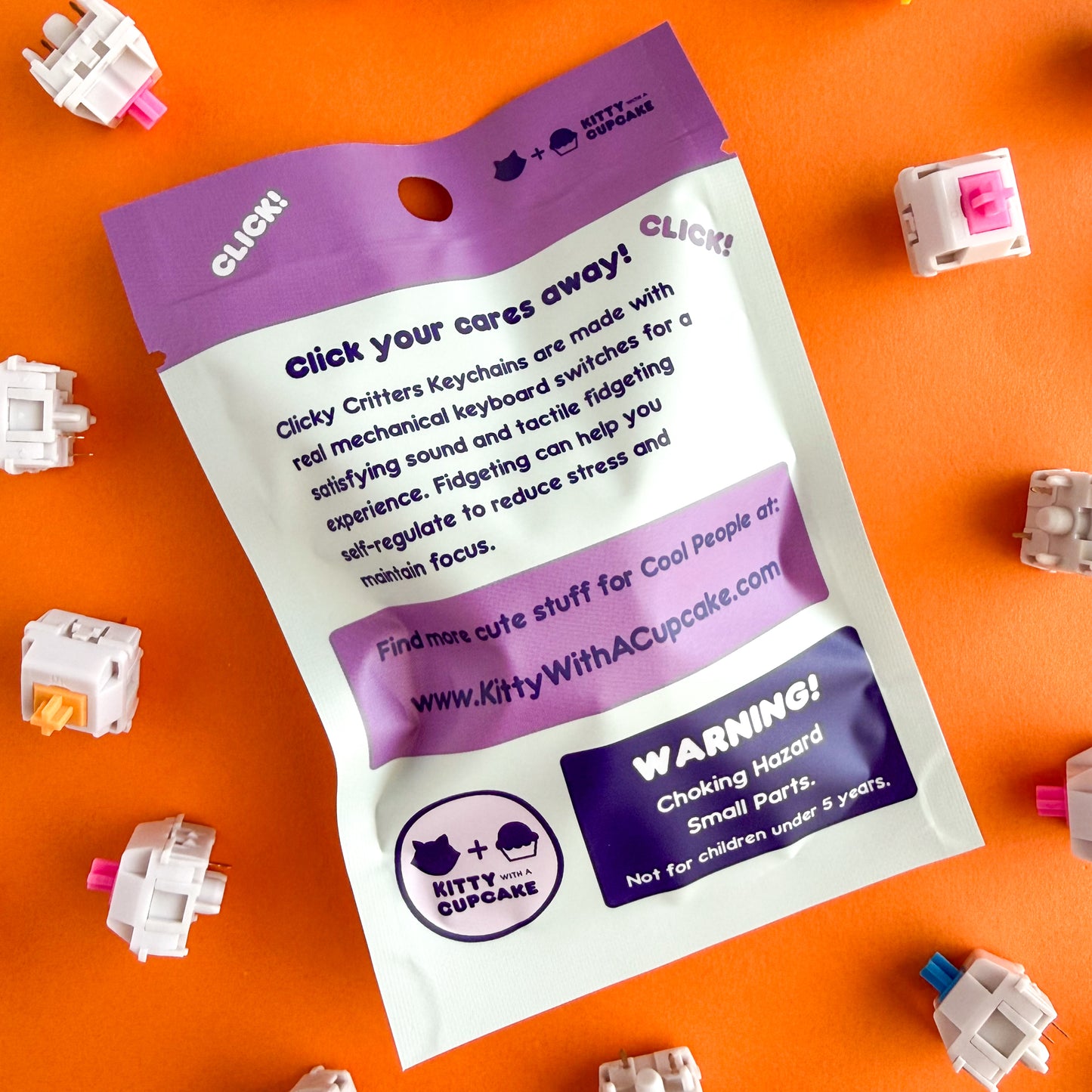 The back of the Clicky Critters Blind Bag, it reads "Clicky your cares away! Clicky Critters Keychains are made with real mechanical keyboard switches for a satisfying sound and tactile fidgeting experience. Fidgeting can help you self-regulate to reduce stress and maintain focus." The bag is mint with a purple top. 