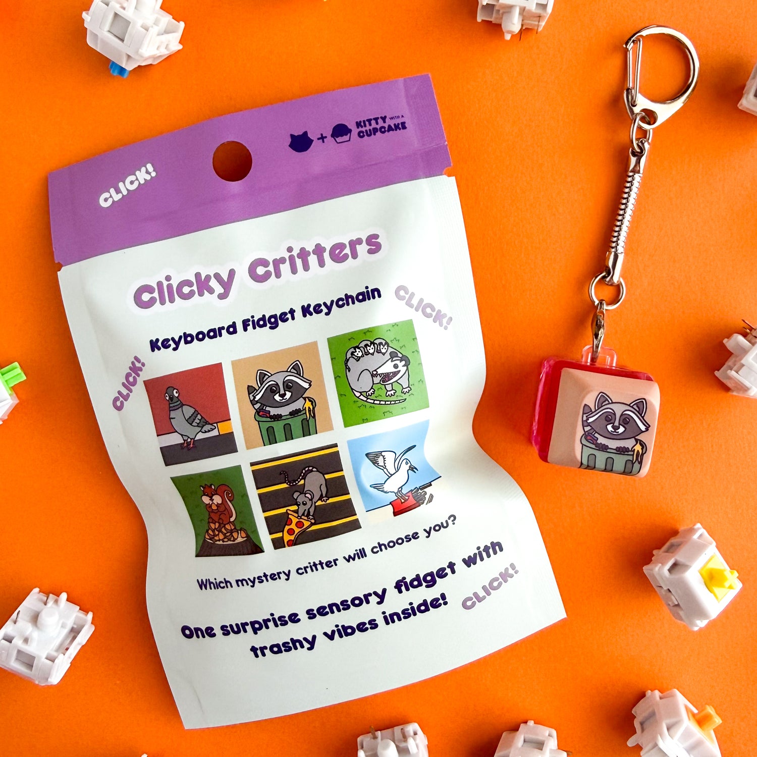 A blind bag package that is mostly mint colored with a purple top that reads "Clicky Critters - Keyboard Fidget Keychain" it has pictures of potential design options including a pigeon, raccoon, opossum, squirrel, pizza rat, and a seagull and reads under these "One surprise sensory fidget with trashy vibes inside!" Next to the bag is a keycap fidget clicker with a keychain attached to it, it has the raccoon in a trash can design on it. The bag and keychain are on an orange background.