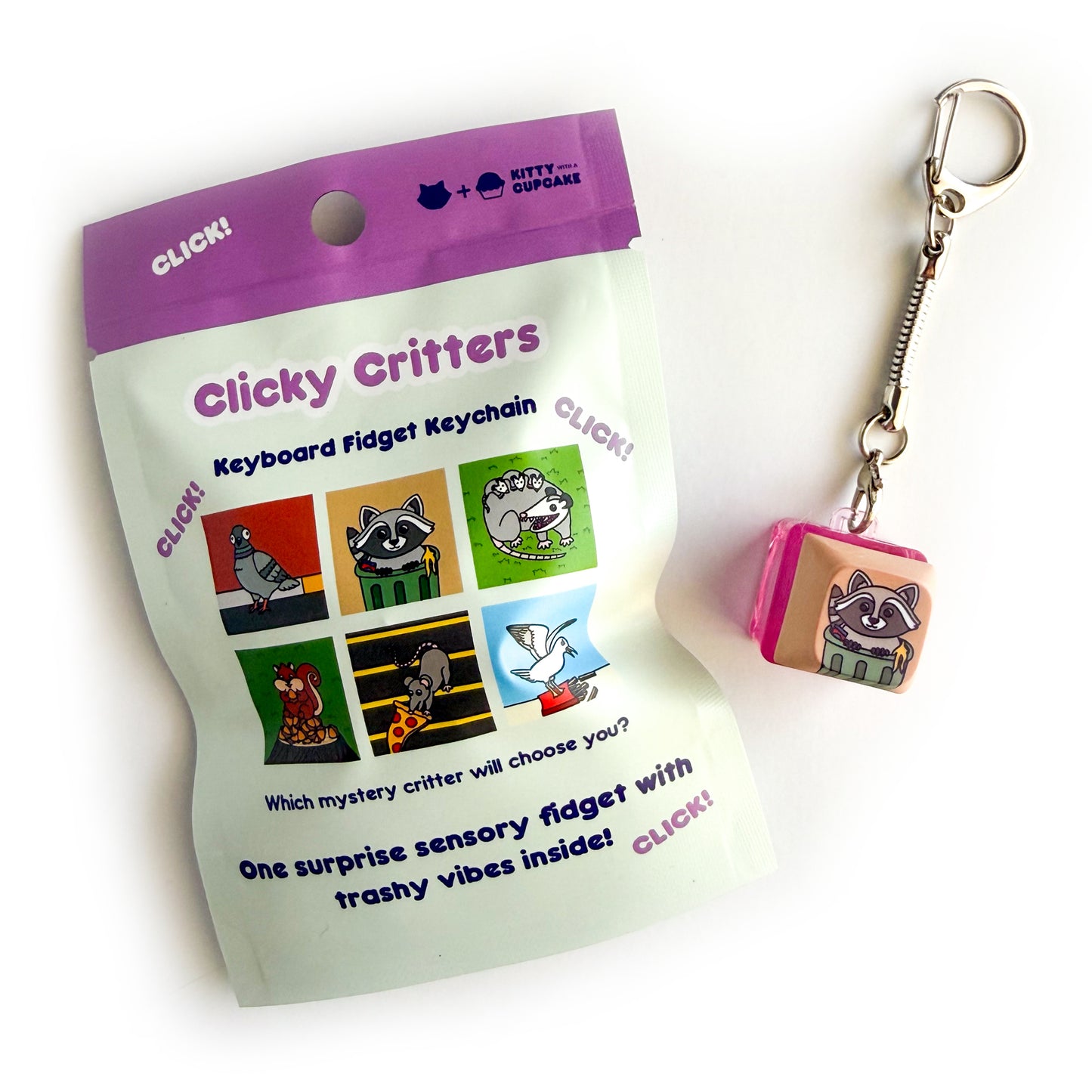 A blind bag package that is mostly mint colored with a purple top that reads "Clicky Critters - Keyboard Fidget Keychain" it has pictures of potential design options including a pigeon, raccoon, opossum, squirrel, pizza rat, and a seagull and reads under these "One surprise sensory fidget with trashy vibes inside!" Next to the bag is a keycap fidget clicker with a keychain attached to it, it has the raccoon in a trash can design on it. 