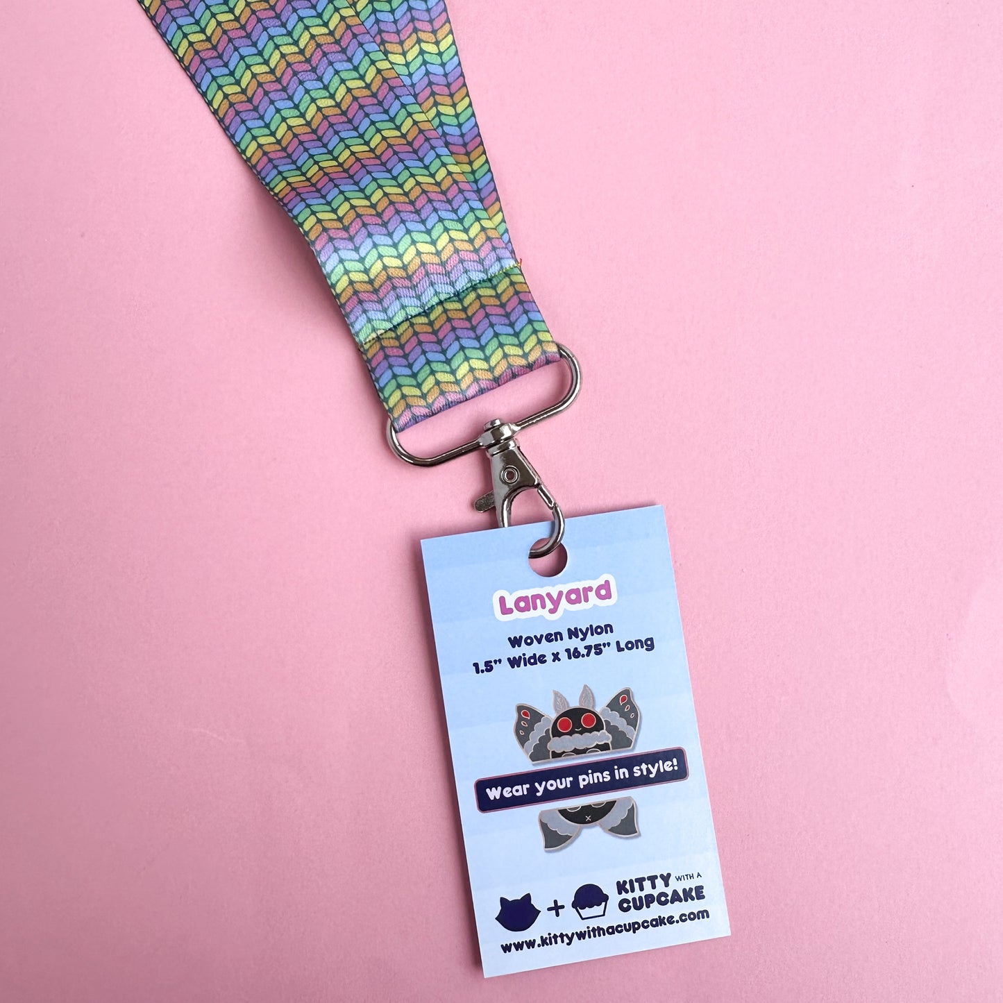 A close up of the rainbow knit lanyard shown with a card clipped to it that reads "Lanyard" and shows the dimensions of the product. 