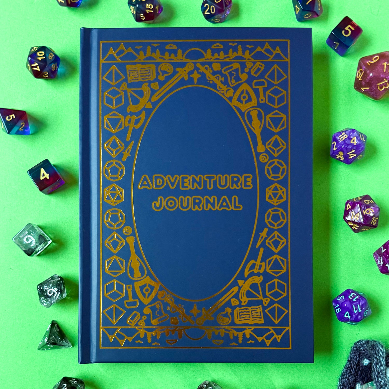 The Adventure Journal displayed on a green background surrounded by dice. 